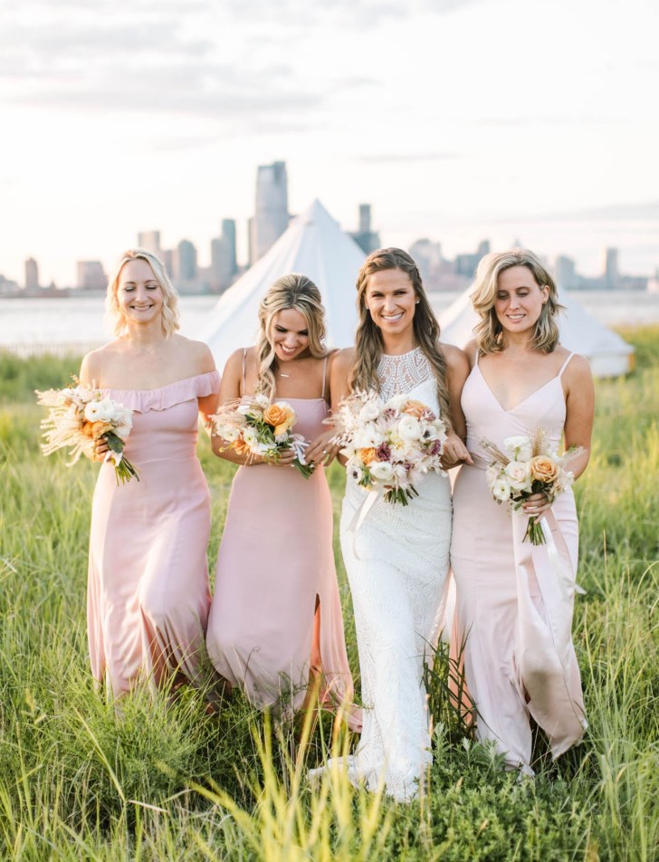 bridal party walking together while wearing light pink floor length bridesmaid dresses