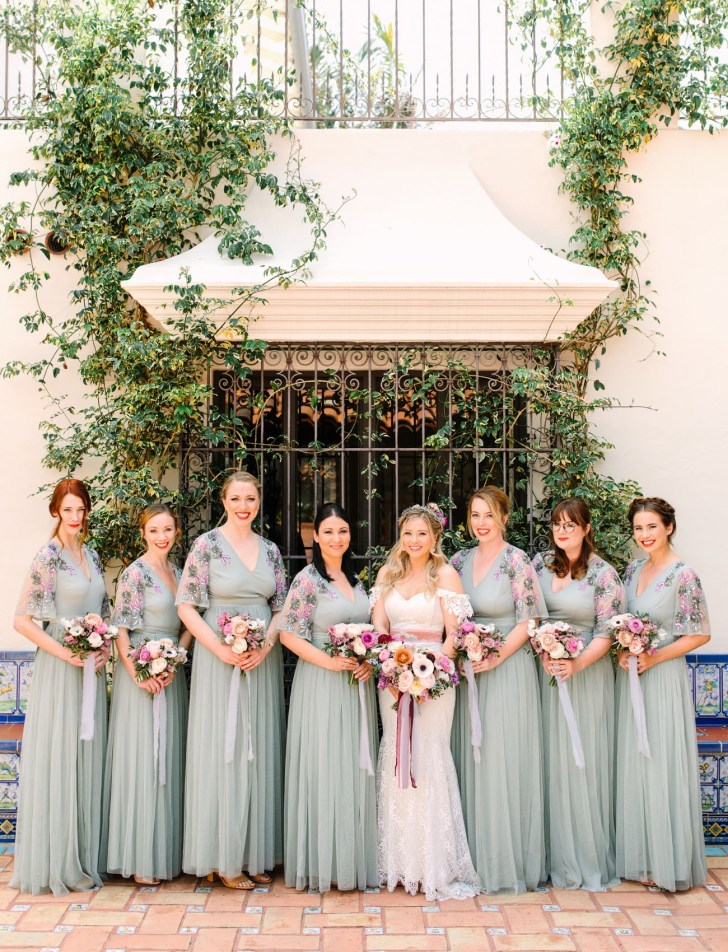 bridal party standing in front of an ivy covered building wearing springtime floral bridesmaids dresses online from ASOS