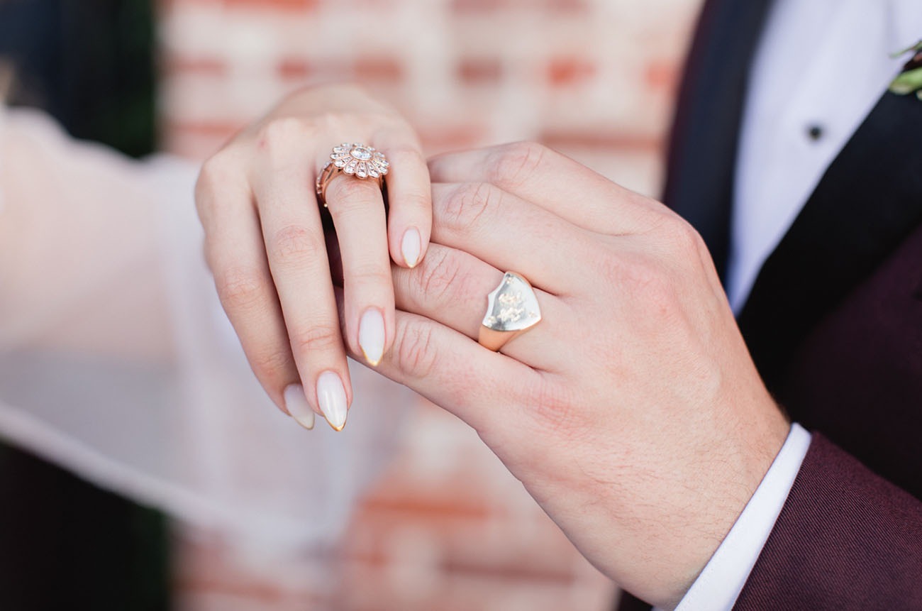 groom wearing a gold crest wedding band on his ring finger
