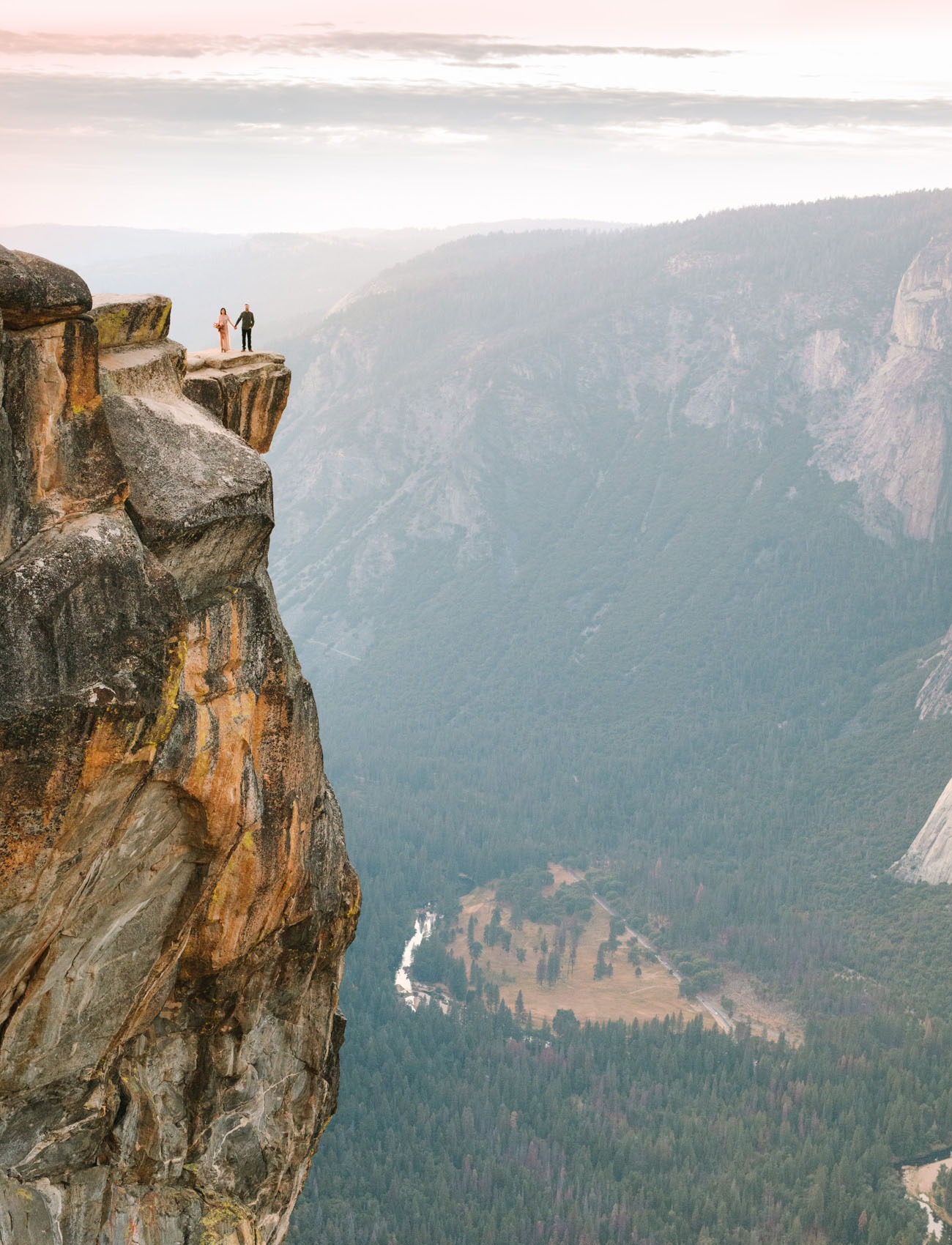 couple standing on the edge of a cliff in Yosemite, an epic honeymoon destination