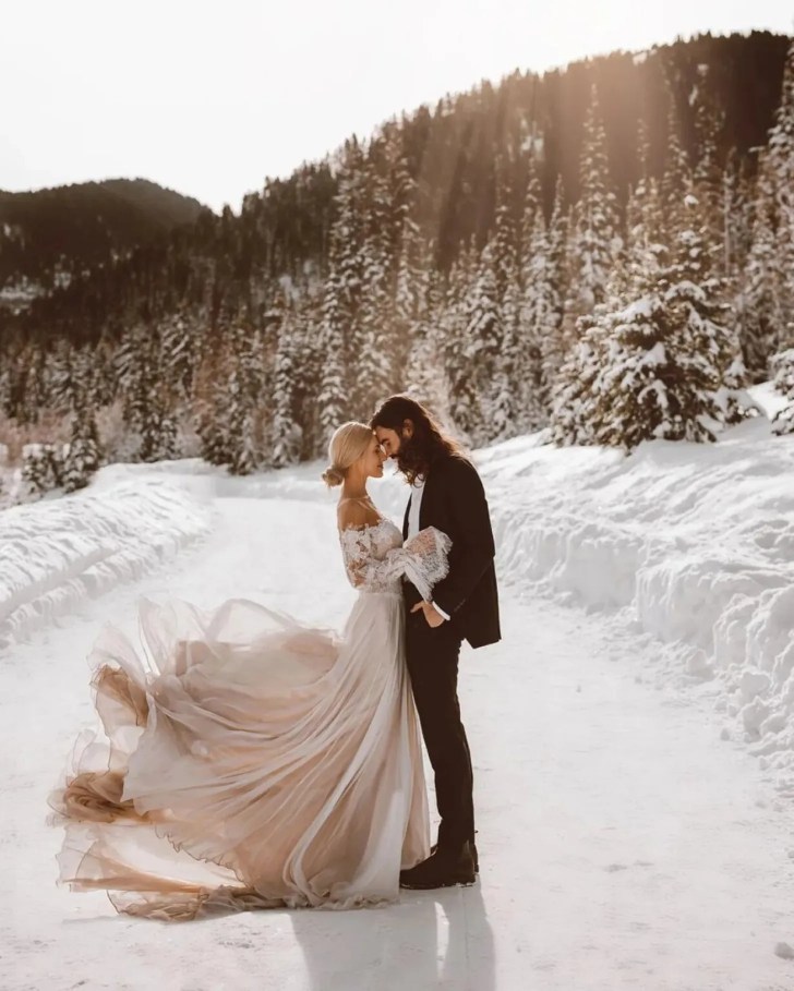 couple hiking up a snowy trail in their wedding clothes winter wonderland best Christmas wedding ideas