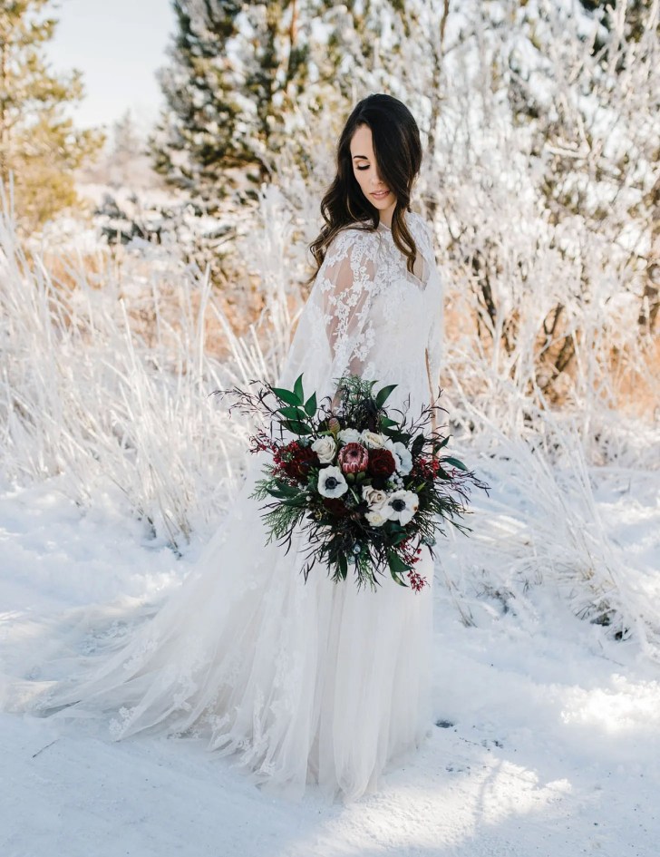 winter wonderland best Christmas wedding ideas where bride is wearing a vintage lace cape