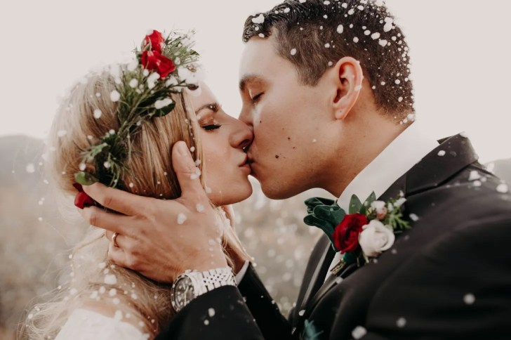 winter wonderland best Christmas wedding ideas where bride wears a red rose flower crown during a white snowy ceremony